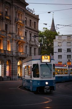 Tram number 13 navigating through Paradeplatz with classic Zurich architecture at dusk.
