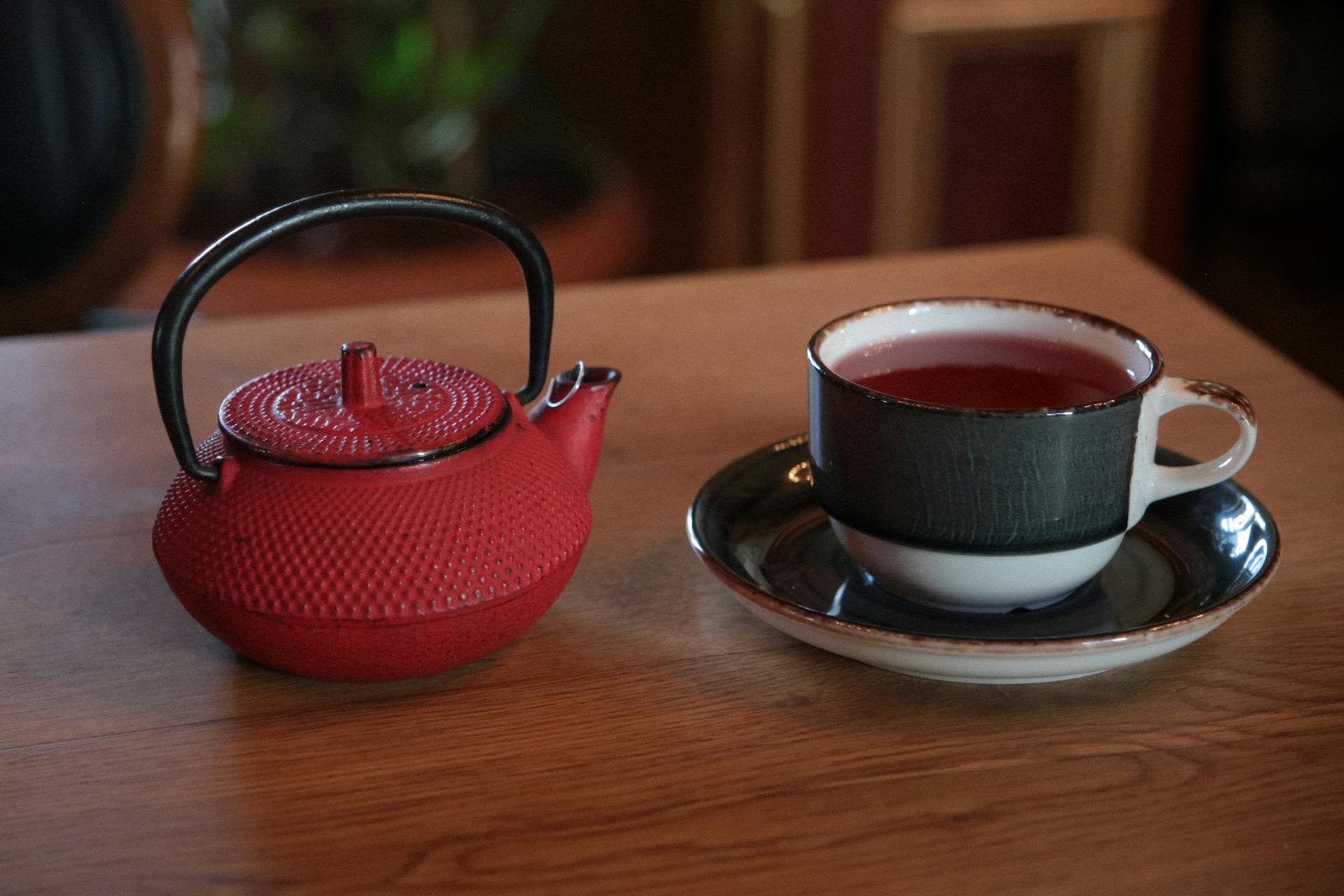 Red Teapot and Black Teacup on Wooden Table