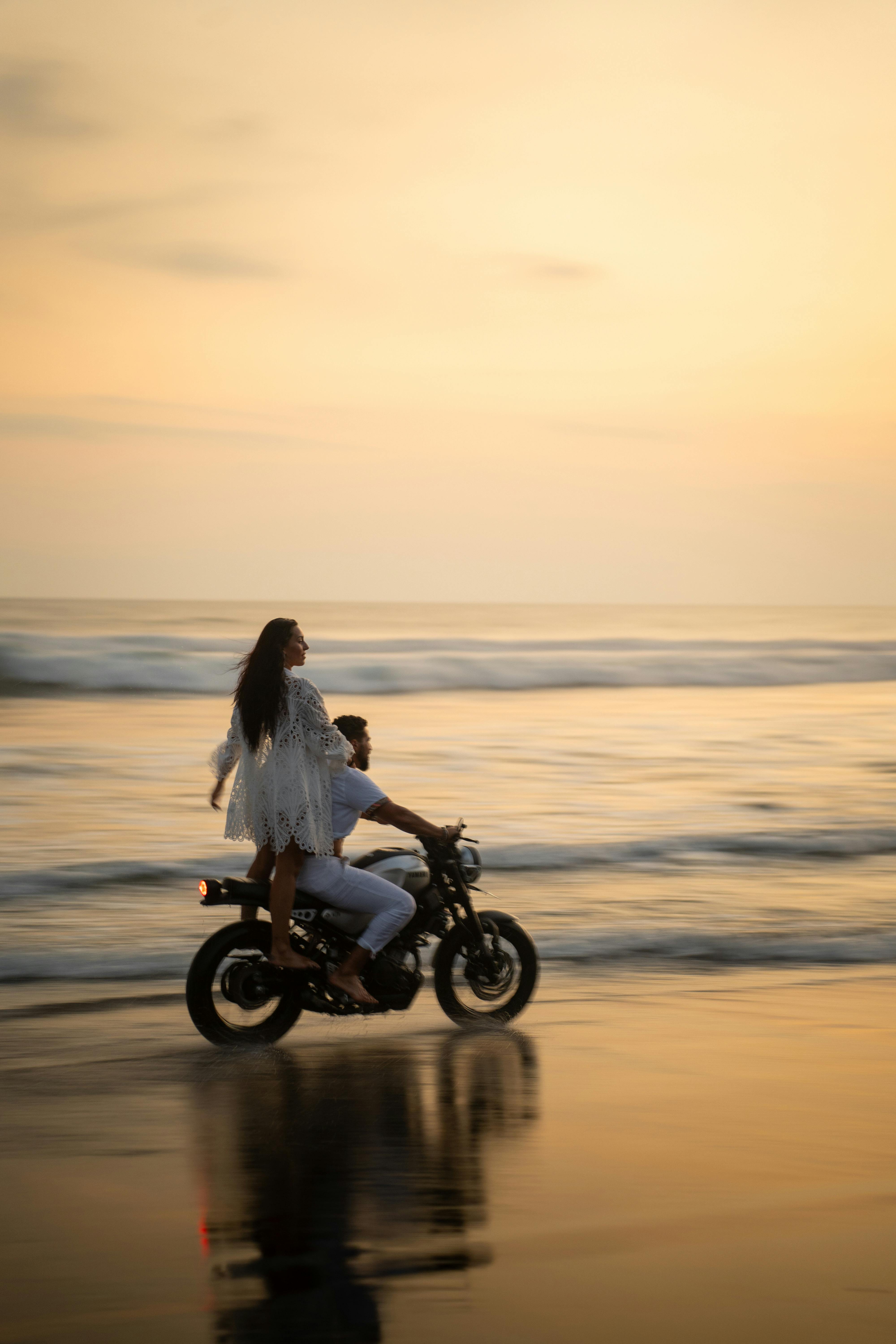 Couple enjoying a motorbike ride on the beach during a stunning Bali sunset.