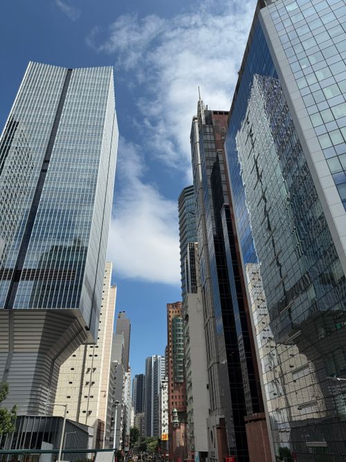 Free Tall skyscrapers reflecting bright blue sky and clouds in urban cityscape. Stock Photo