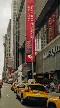 Yellow taxis lined up in vibrant Times Square under tall buildings, New York City.