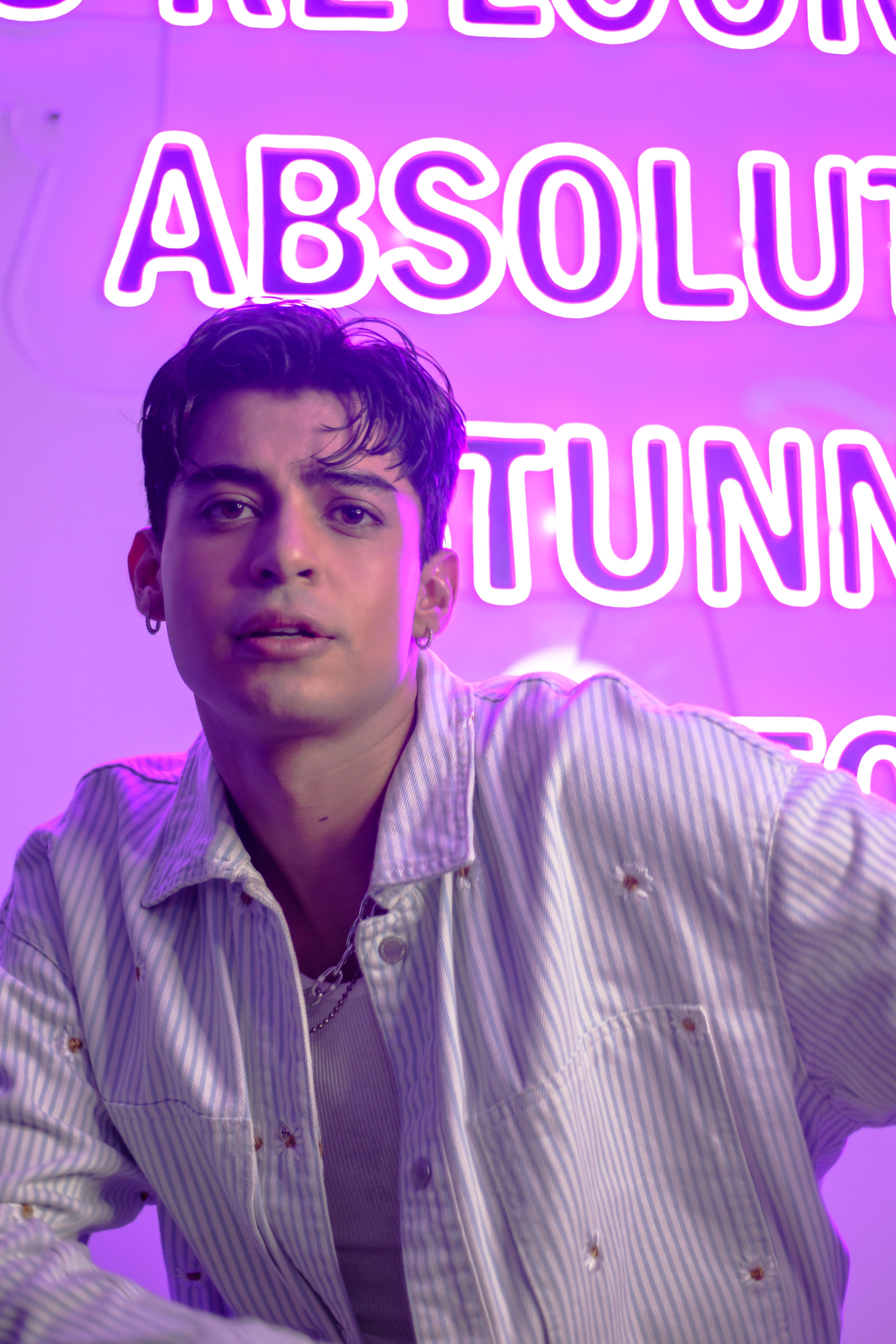 Portrait of a young man in a striped shirt with neon lights in Ciudad de México, CDMX, México.