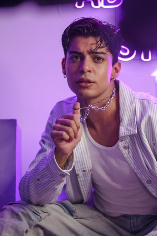 Free Portrait of a young man in casual attire with vibrant neon lights in the background, CDMX. Stock Photo