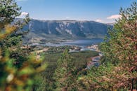 晴朗的蓝天下，一个高山湖泊被郁郁葱葱的松树环绕，景色壮丽