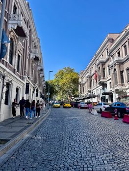 Cobblestone street lined with historic buildings under a clear blue sky in a bustling urban setting.