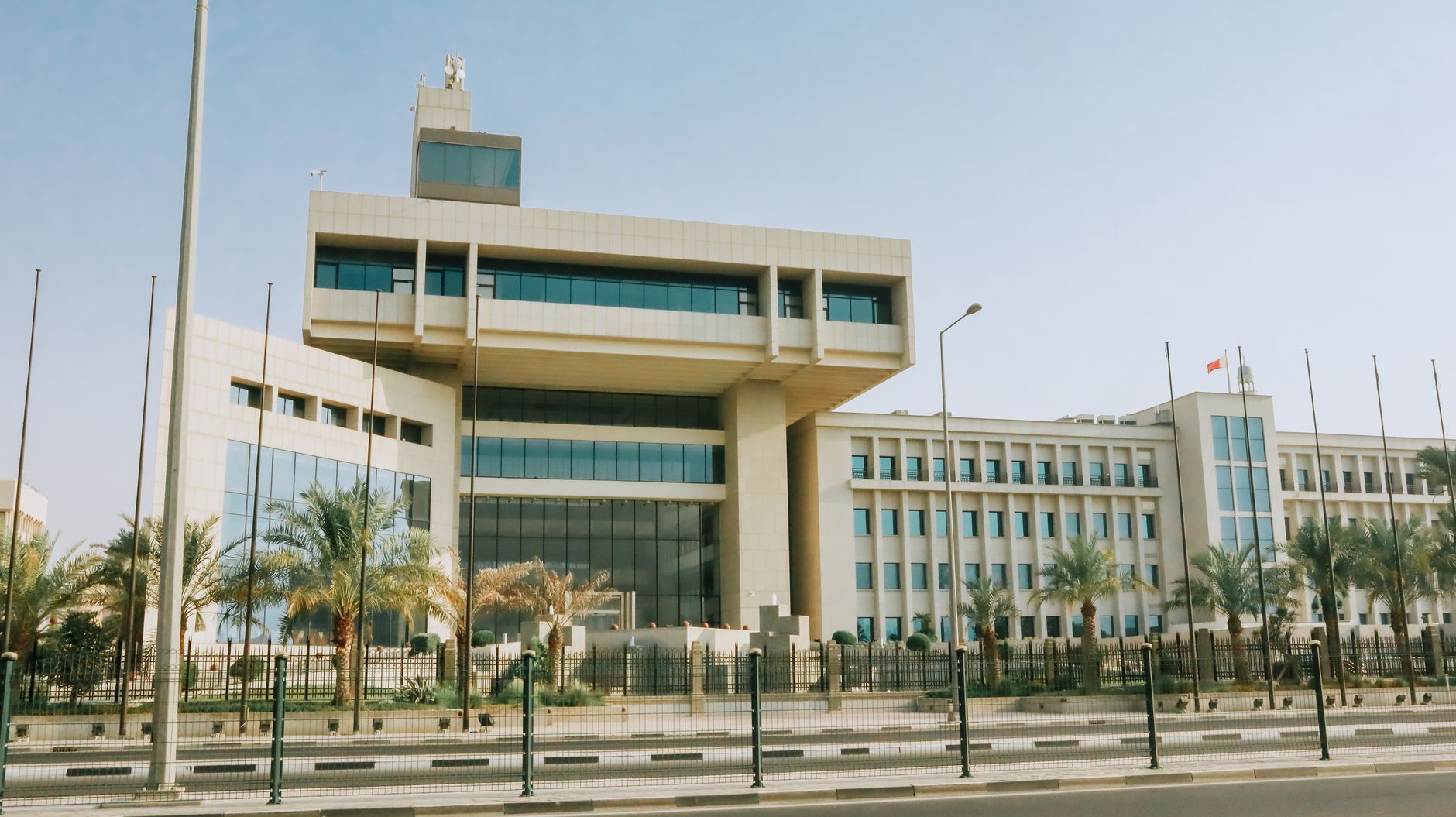 Modern office building with palm trees under a clear sky.