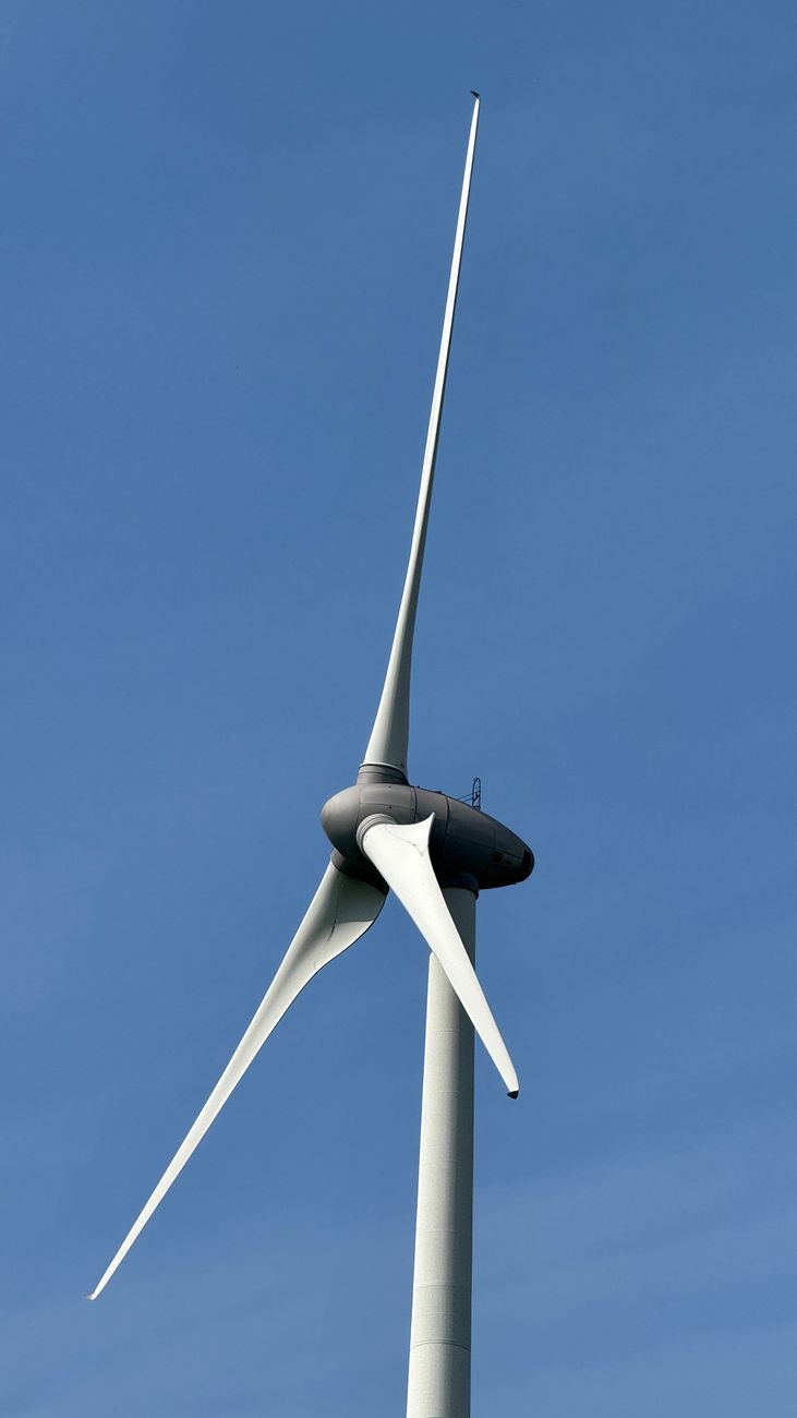 Een eenzame windturbine staat trots tegen een heldere blauwe lucht in Zeewolde, Nederland.