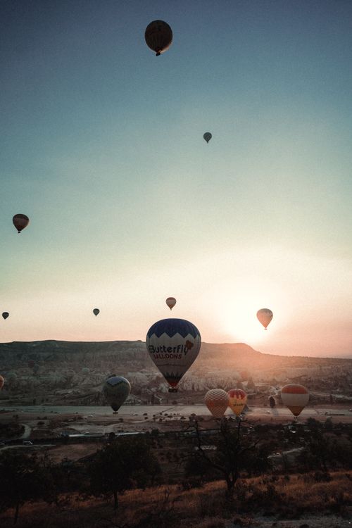 Free Hot air balloons soar over Cappadocia's unique landscape at sunrise, a magical view. Stock Photo