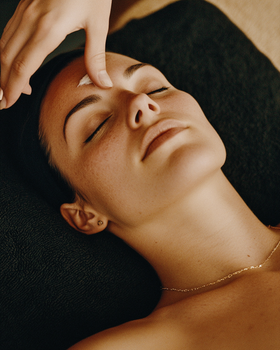 Peaceful woman enjoying a rejuvenating facial treatment with warm ambiance.