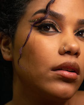 Close-up portrait of a woman with artistic eye makeup and a nose ring, showcasing creativity and elegance.