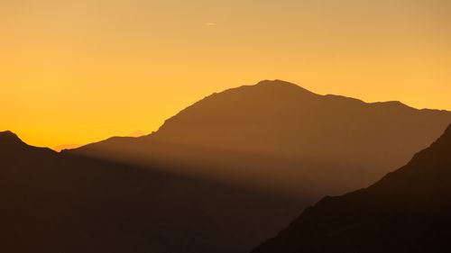 Free Beautiful sunrise casting warm light over the silhouetted mountain range with dramatic sky Stock Photo