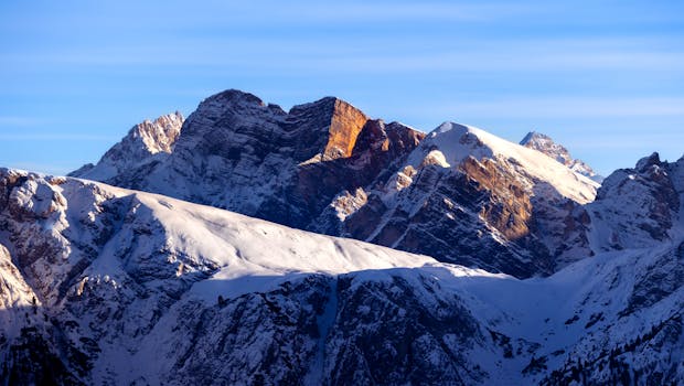 Capture of the awe-inspiring Dolomites with sunlit peaks against a vibrant sky.