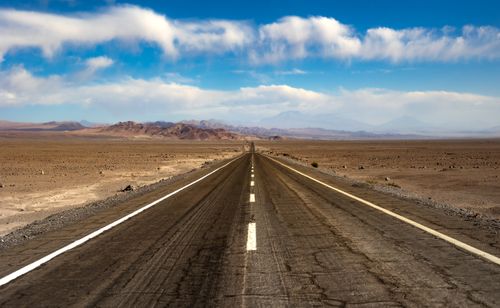 Free A scenic highway stretches through the Atacama Desert in Chile, with mountains in the background under a bright blue sky. Stock Photo