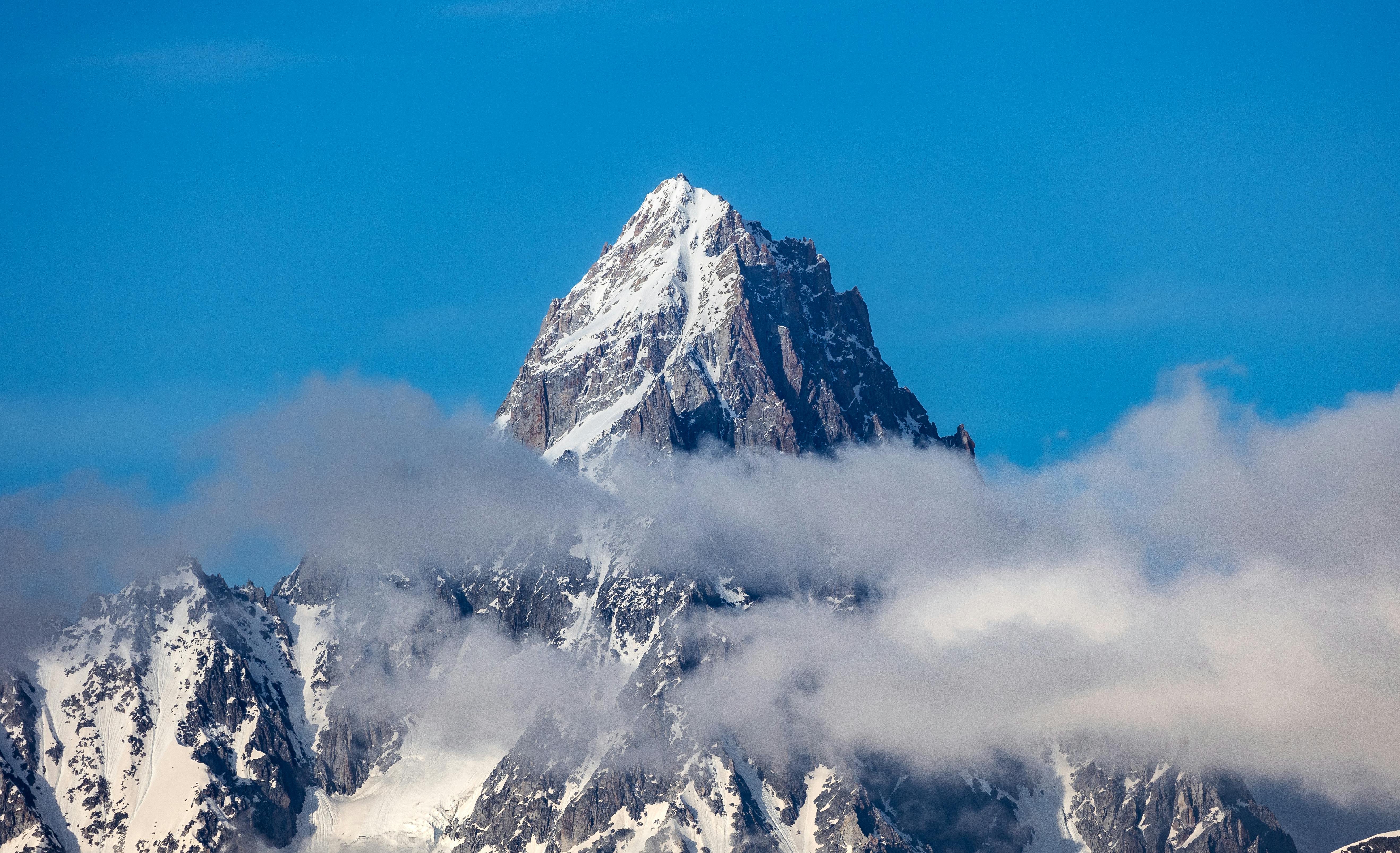 Prescription Goggle Inserts - A breathtaking view of the snowy peak of Mont Blanc surrounded by clouds under a bright blue sky.