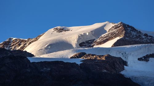Free Breathtaking snow-covered peaks of the Alps illuminated by sunlight with a clear blue sky background. Stock Photo
