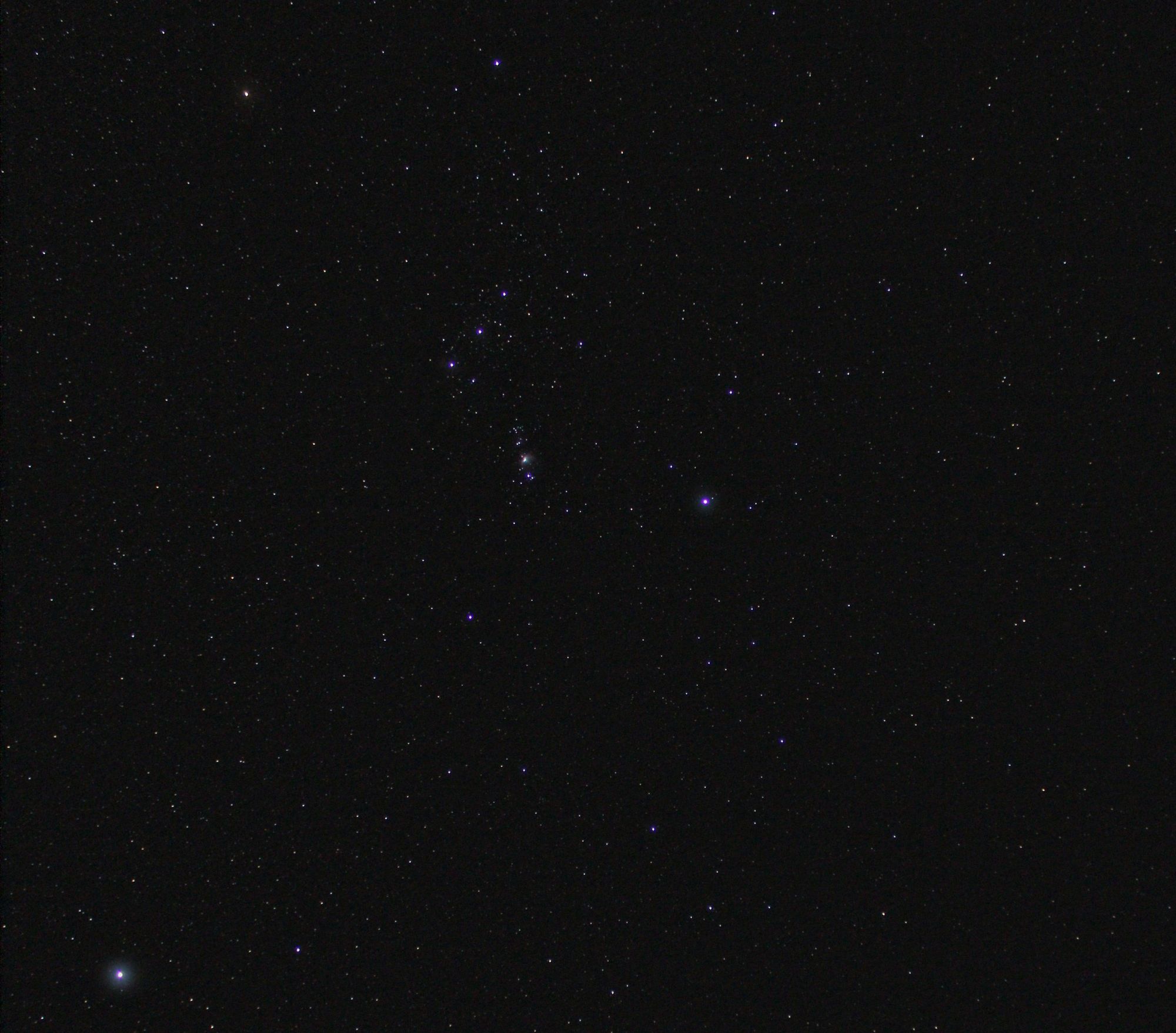 Imagen telescópica con un patrón moteado de zonas claras y oscuras; un círculo blanco en el centro marca el tamaño de Betelgeuse, que fue retirada de la imagen, y abajo a la izquierda destaca un punto brillante