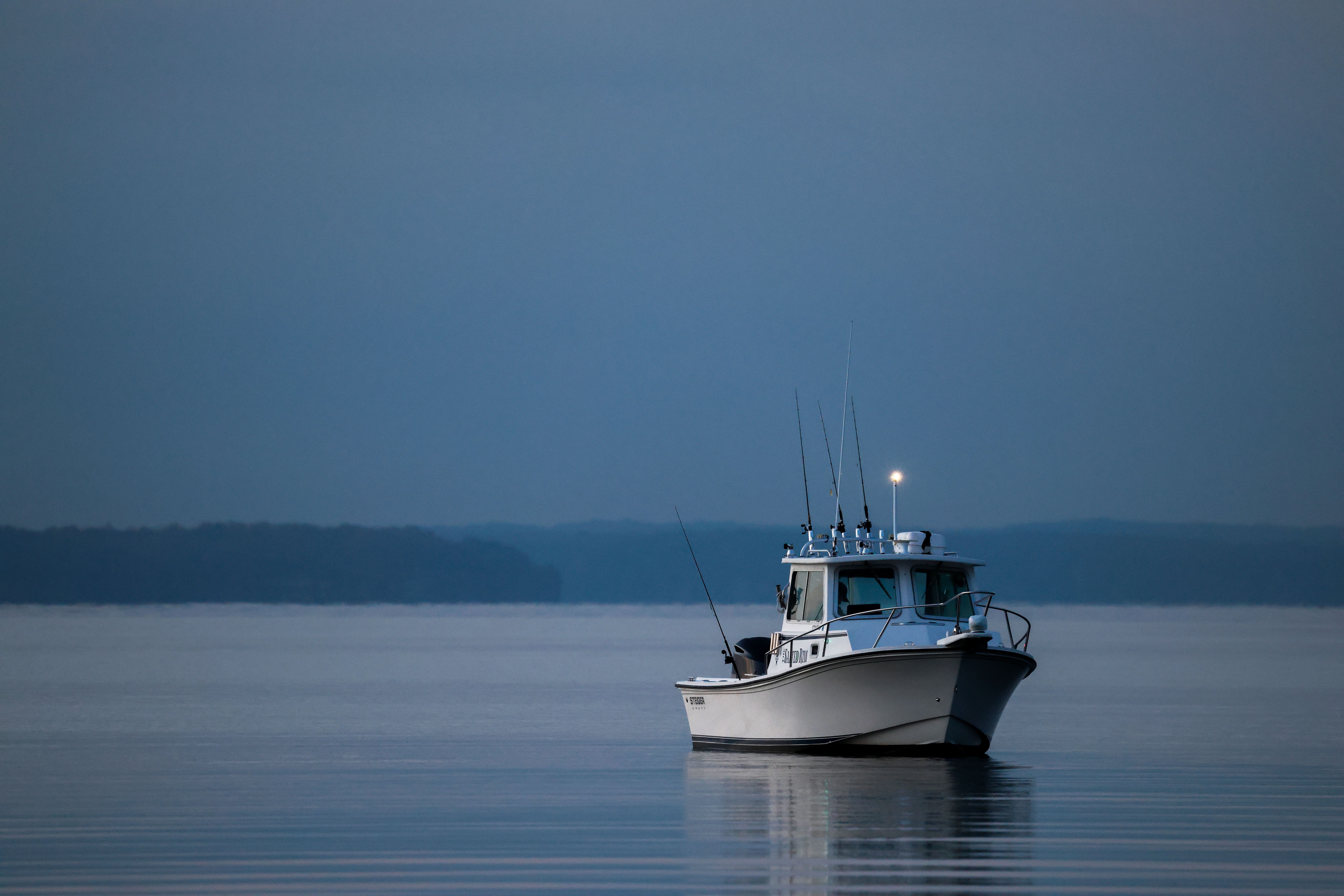 A serene fishing boat floats peacefully at twilight in Stamford's tranquil waters.