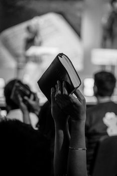 Monochrome image of a religious congregation in Jakarta, Indonesia, with raised Bibles.