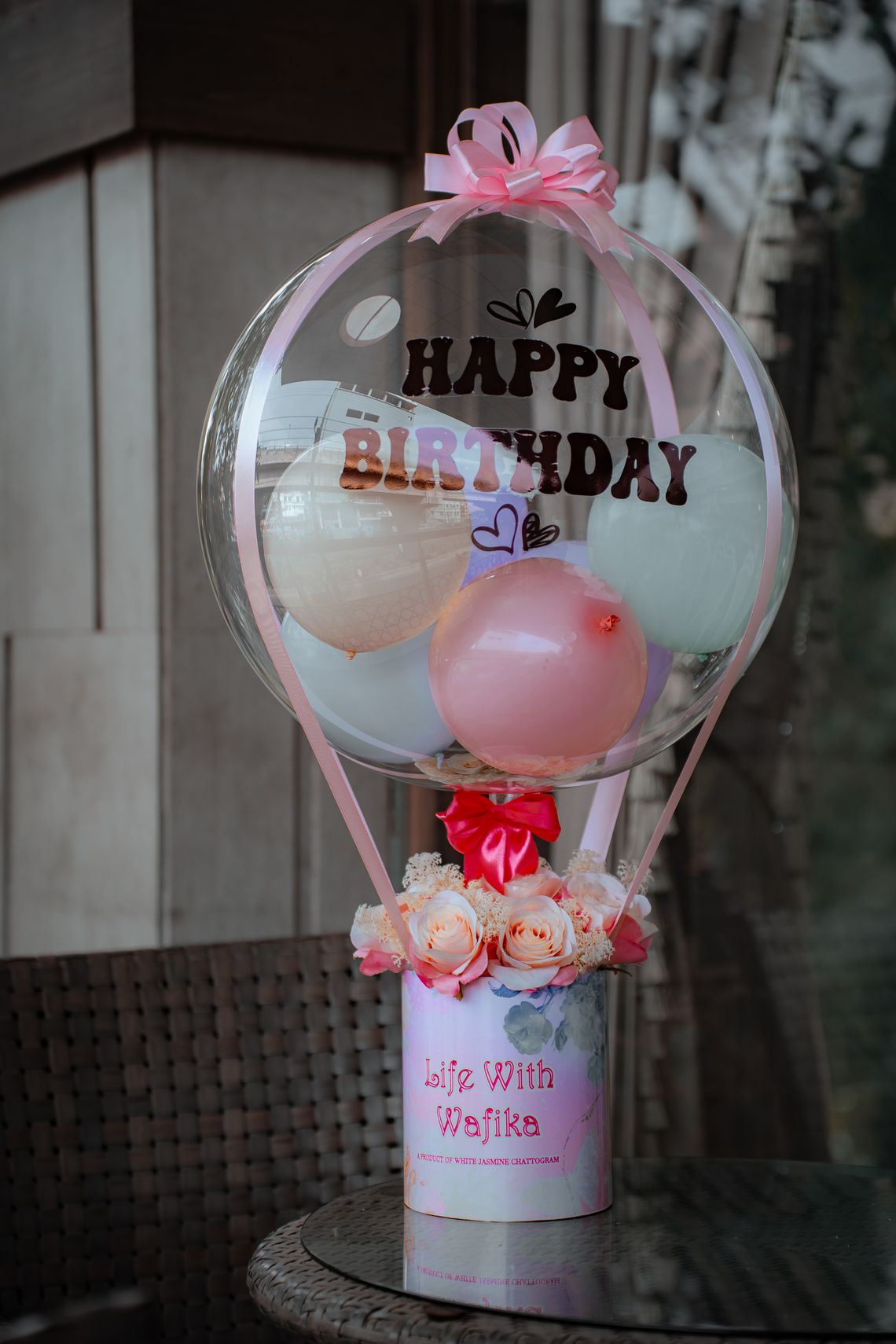 Elegant pastel birthday balloon arrangement with gift boxes and floral accents