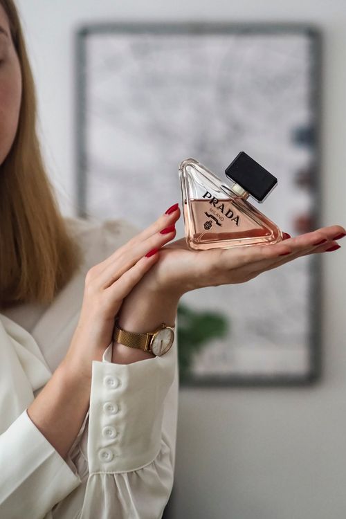 Free Woman elegantly displaying Prada perfume, highlighting luxury fashion and style. Stock Photo