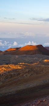 Stunning view of mountain peaks illuminated by a golden sunset on Hawaii's volcanic landscape.