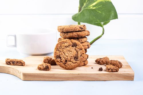 Free Close-up of chocolate chip cookies on a wooden board with a cup in the background. Stock Photo