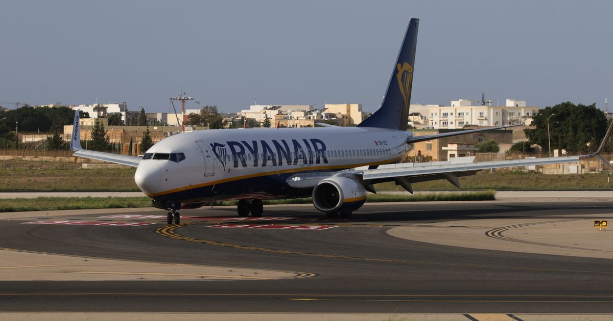 A passenger jet taxiing on an airport runway in sunny weather.
