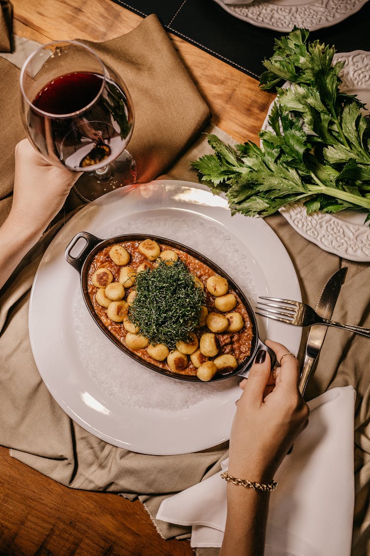 Plate Of Food Next To Glass Of Red Wine