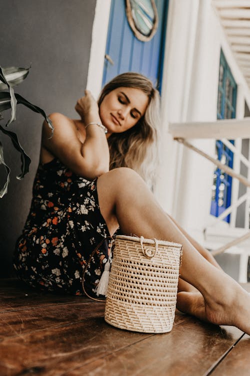 Woman Wearing a Floral Sleeveless Dress Sitting on  Wooden Floor