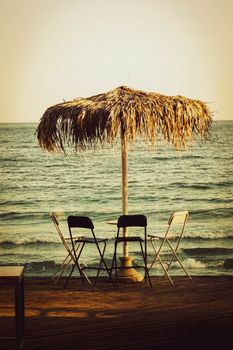 Peaceful beachfront view with straw umbrella and chairs, perfect for a vacation getaway.