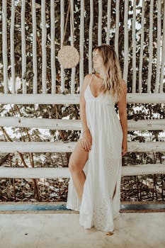 身着白色连衣裙的时尚女性，在质朴的背景下摆出姿势，营造出一种轻松时尚的氛围