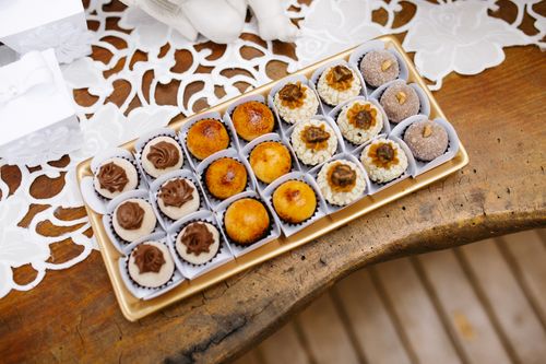 Free A selection of gourmet pastries displayed on a rustic wooden table with lace decor. Stock Photo