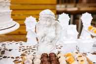 A decorative angel statue surrounded by cakes and desserts on a table setting, perfect for events.