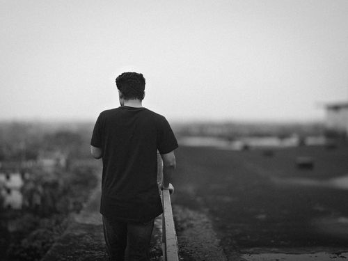 Free A black and white photo of a man in casual attire walking alone in a foggy environment. Stock Photo