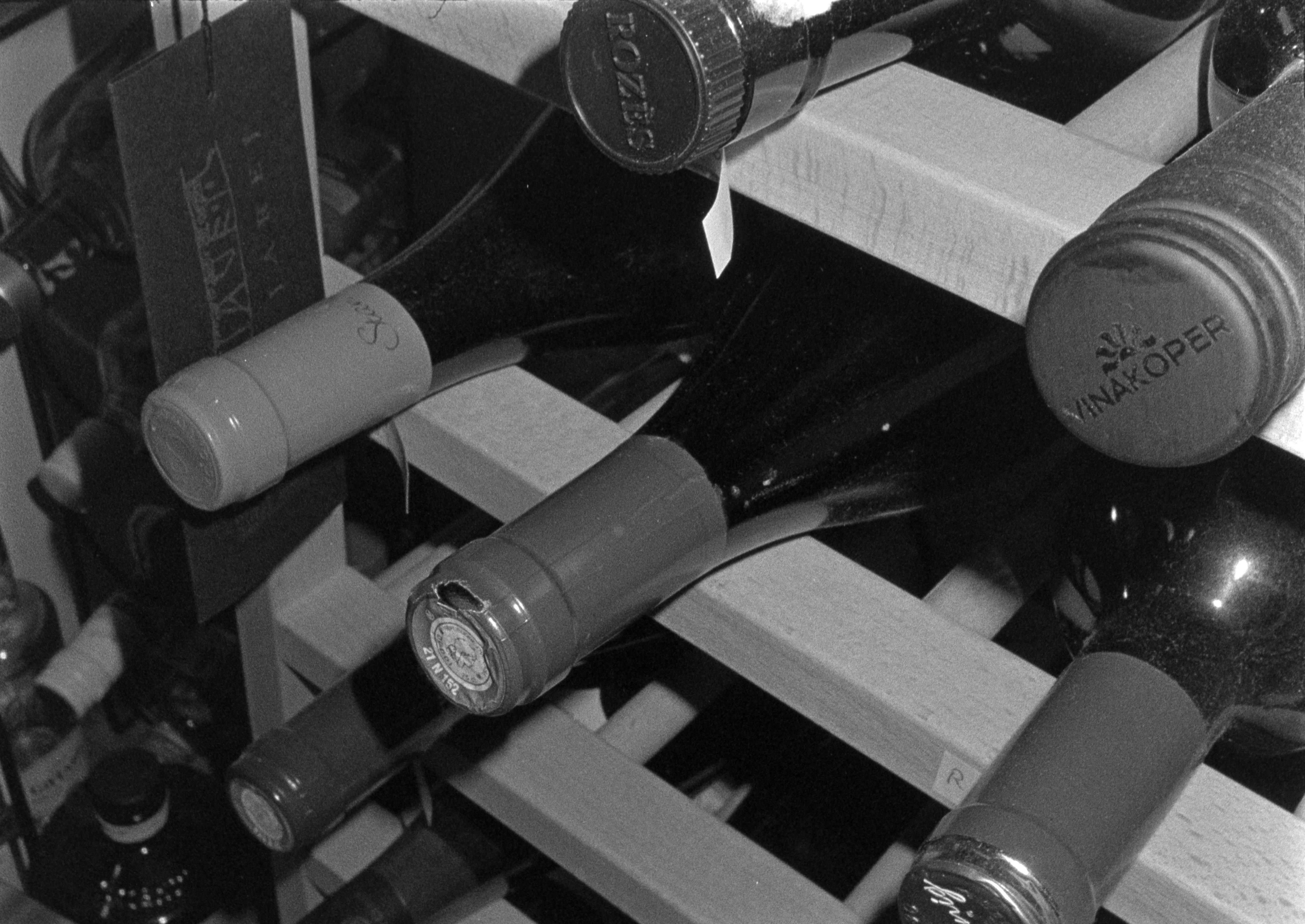 Monochrome image of wine bottles stored on a wooden rack evokes a classic and elegant atmosphere.