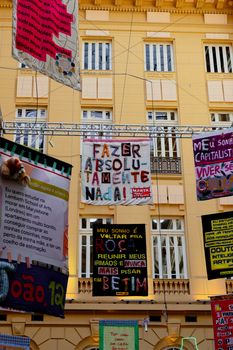 Colorful protest flags hang in Belo Horizonte, showcasing public messages.