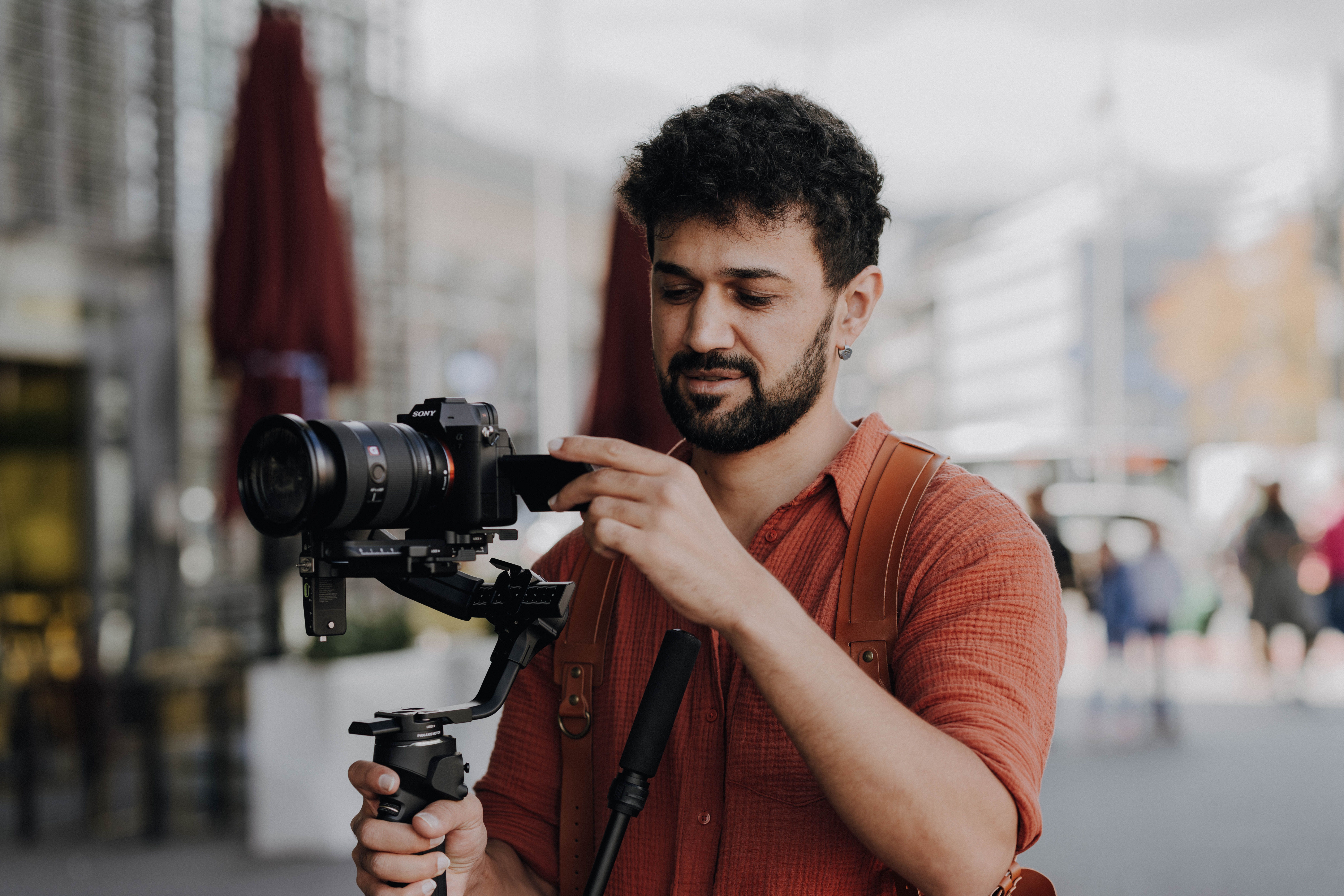 Videographer Operating Camera with Gimbal Outdoors · Free Stock Photo