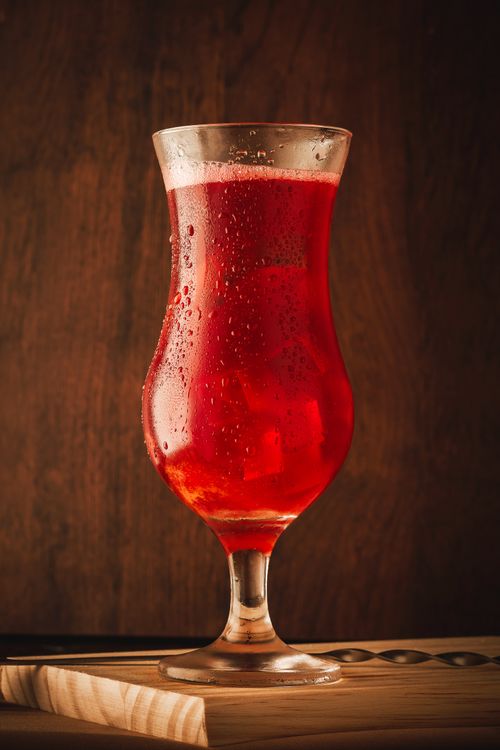 Free Close-up of a red cocktail in a glass with condensation on a wooden surface. Stock Photo