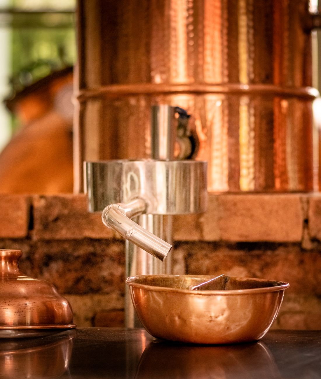 A copper still and copper bowl in a small distillery