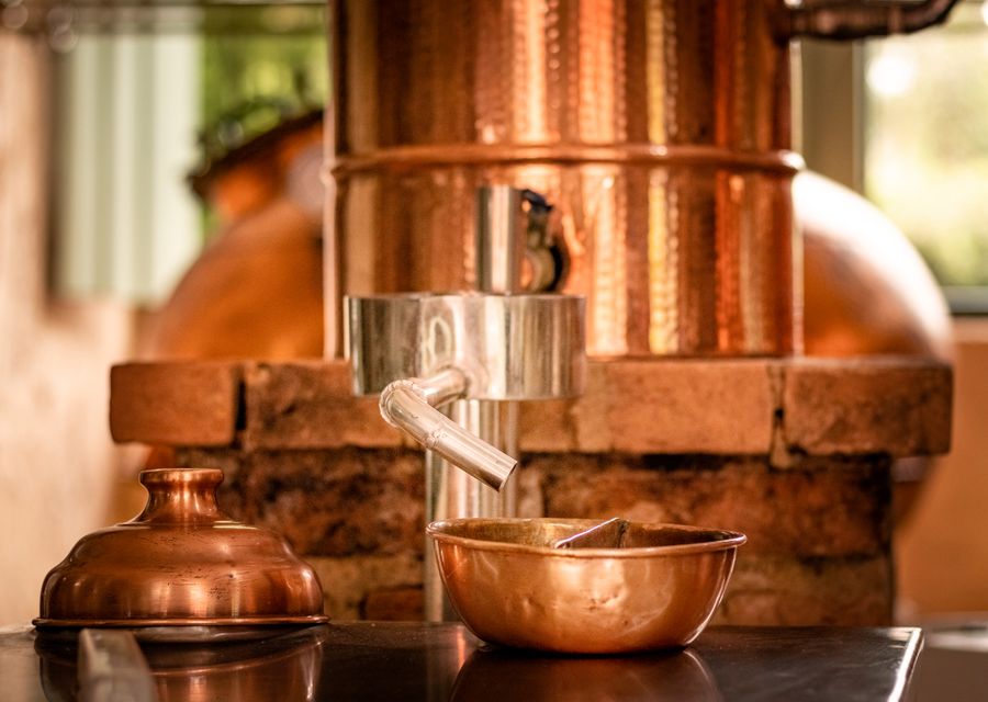 A copper still and copper bowl in a small distillery