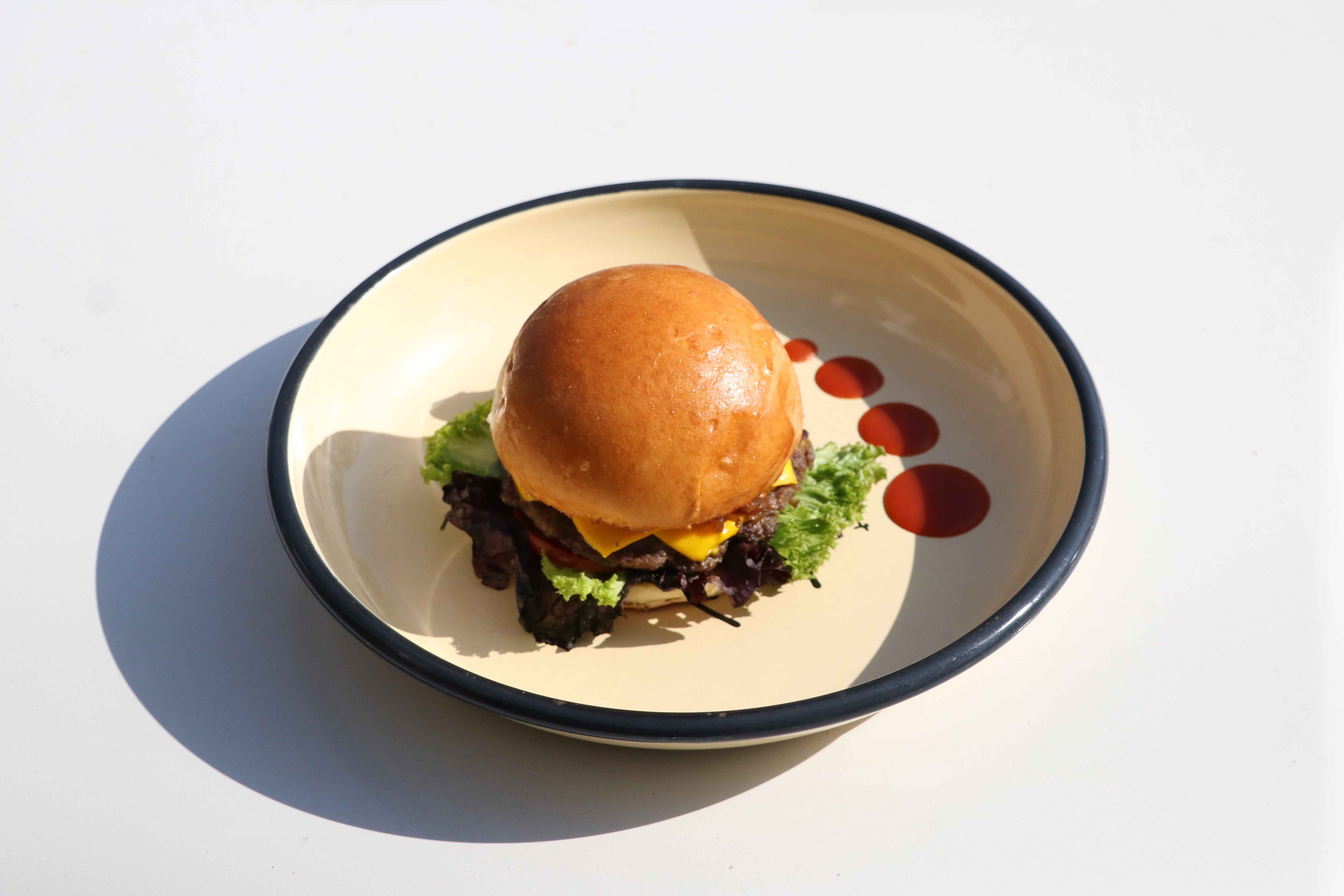 Delicious gourmet cheeseburger with lettuce on an artistic plate, perfect for foodies.