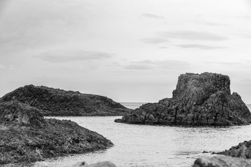 Free Monochrome image of rugged coastal rock formations protruding from the sea. Stock Photo