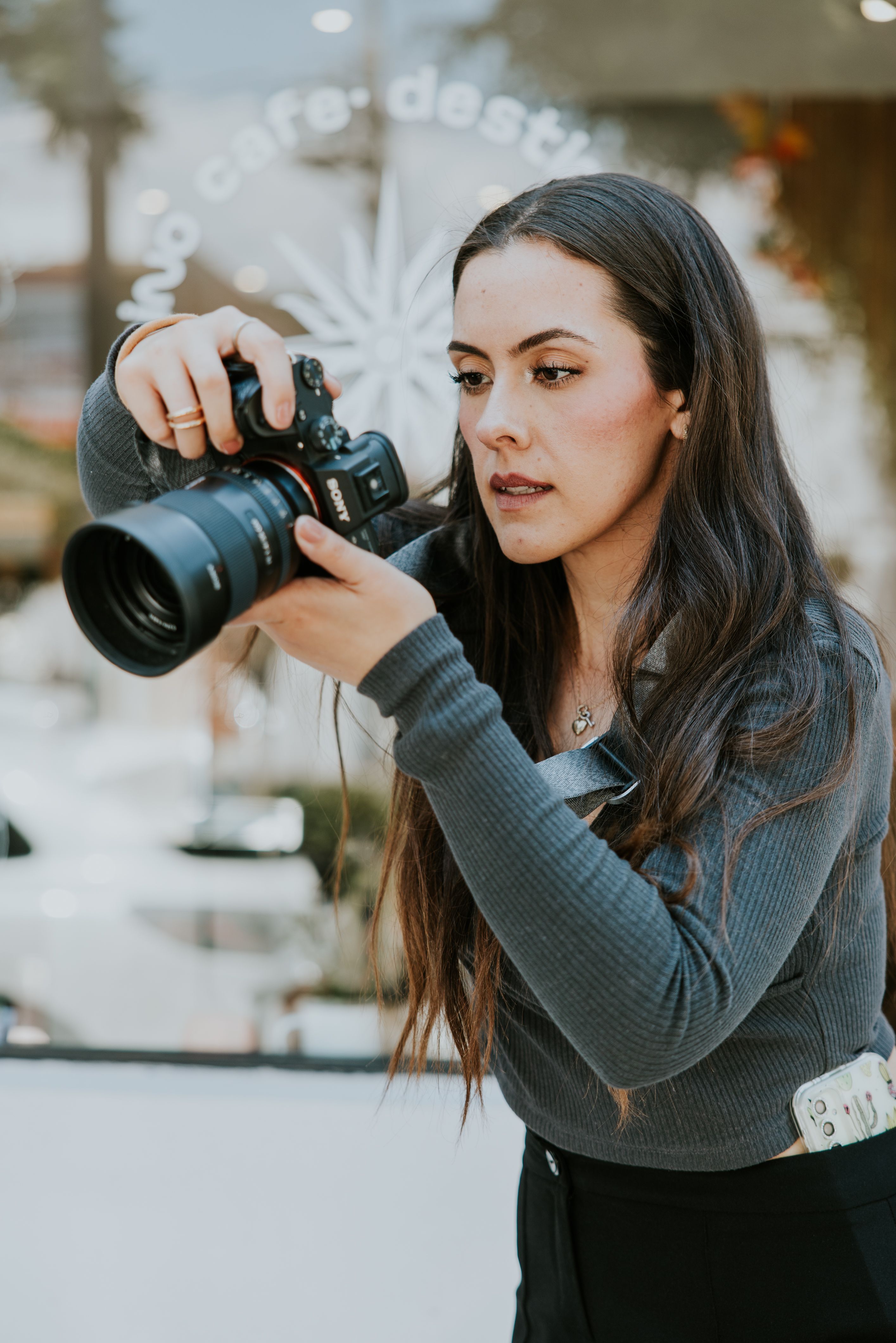 A focused young female photographer capturing moments inside a cozy cafe.