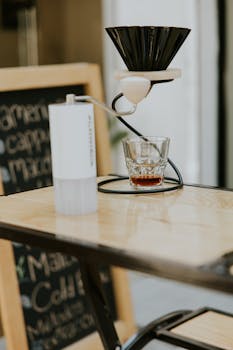 Close-up of a pour over coffee setup on a wooden table in a cafe setting.