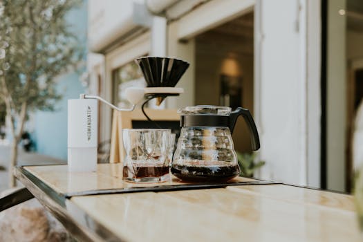 A stylish outdoor café setup with coffee accessories on a wooden table.