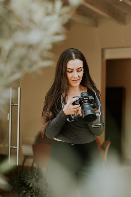 Free Woman photographer reviewing shots in a stylish cafe setting. Stock Photo