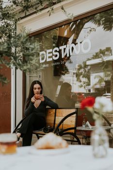 Woman enjoying coffee at an outdoor cafe with a tranquil ambience.