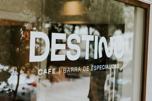 Reflective window with "Destino" cafe sign and blurred interior view.
