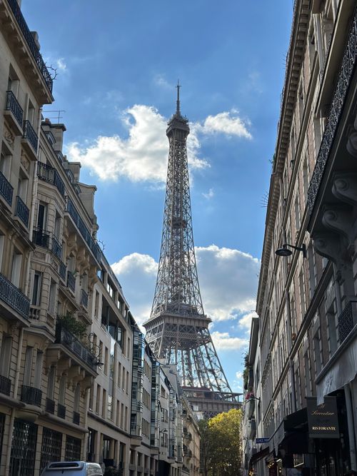 Free Charming Paris street scene with the Eiffel Tower under a clear blue sky. Stock Photo