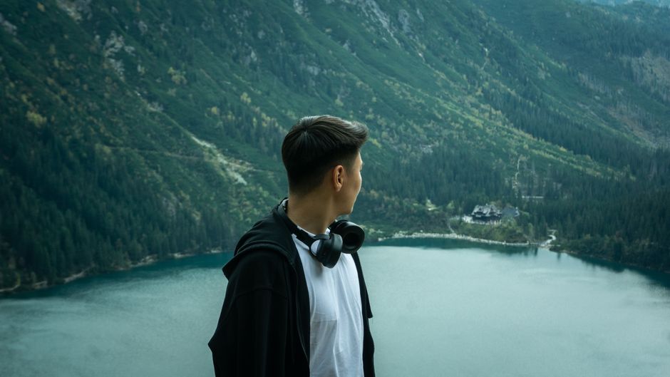 A man looks over the serene Morskie Oko lake surrounded by lush forests in Lesser Poland.